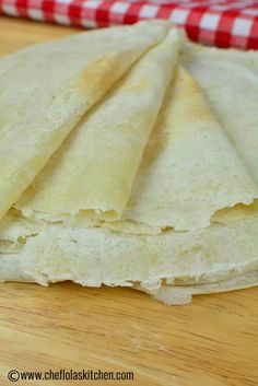 some tortillas are sitting on top of a cutting board with a red and white checkered napkin