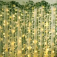 a bed with green vines on the wall and lights hanging from it's sides