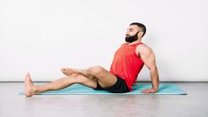 a man sitting on top of a blue mat in the middle of a yoga pose