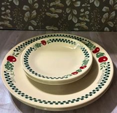 three white plates with green and red designs on them