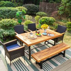 a wooden table with four chairs and a bench in the middle of a backyard area