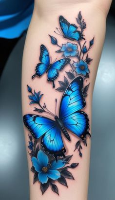 a blue butterfly tattoo on the thigh with flowers and leaves around it, as well as butterflies