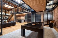 a pool table in the middle of a living room with stairs leading up to an open floor plan