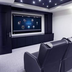 a home theater with black leather seats and a flat screen tv mounted on the wall