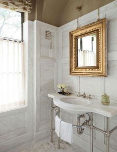 a bathroom with a sink, mirror and towel rack in it next to a window