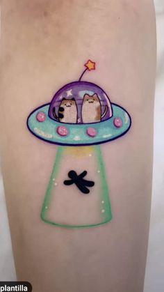 an alien tattoo with two cats sitting on it's side, in the shape of a spaceship