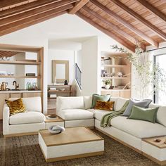 a living room filled with white furniture and lots of wood beams on the ceiling,