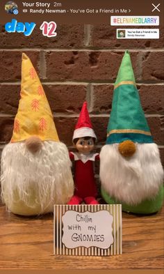 three gnomes sitting on top of a table next to a sign