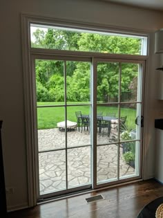 an open sliding glass door leading to a patio with table and chairs in the background