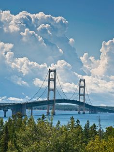 a large bridge spanning over the ocean under a cloudy blue sky with clouds in the background