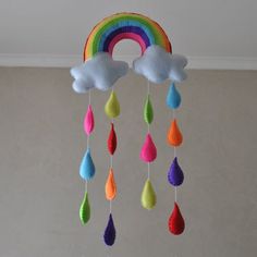 a rainbow mobile hanging from the ceiling with clouds, rain drops and a rainbow painted on it