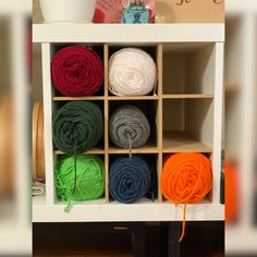 several balls of yarn are sitting in a storage unit on top of a wooden table