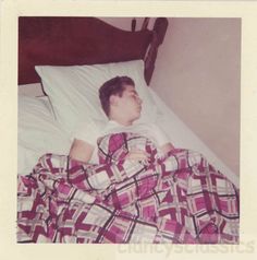 an old photo of a young boy laying in bed with his head on the pillow