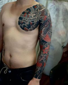 a man with a dragon tattoo on his arm and chest is standing in front of a mirror