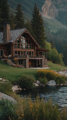 a large house sitting on top of a lush green hillside next to a river and forest