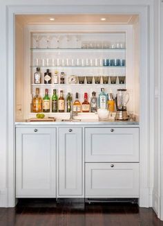 a kitchen with white cabinets and shelves filled with bottles