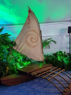 a model sailboat is on display in a room with green lights and palm trees