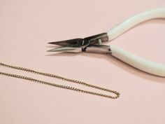 a pair of white scissors sitting on top of a table next to a metal chain