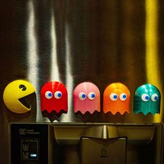 five paco - man shaped objects are lined up on a metal surface, in front of a metallic wall