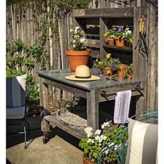 an old wooden table with potted plants on it and a hat sitting on top