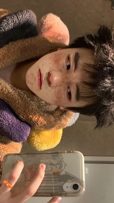 a young boy with freckles on his face holding onto a cell phone screen