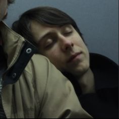 two people sitting next to each other with their eyes closed and one person leaning against the wall