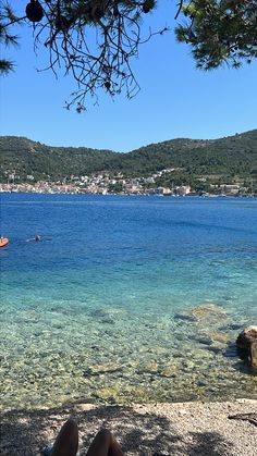 a person is laying on the beach with their feet in the water looking out to sea