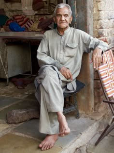 an old man sitting on a chair next to a table