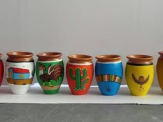 a row of colorful vases sitting on top of a white table next to each other