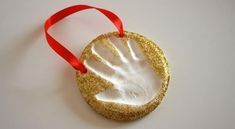 a hand print ornament hanging from a red ribbon on a white table top