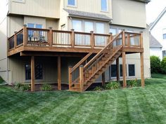 a house with stairs leading to the second floor and another level above it on green grass