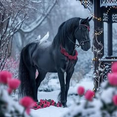 a statue of a horse standing in the snow next to flowers and a gazebo