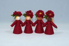 three little red dolls with flowers in their hair, one holding the other's hand