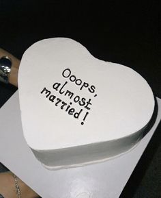 a white heart shaped cake with writing on it