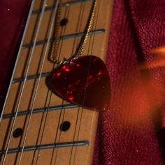 a guitar pick with a chain attached to it sitting on top of a red blanket