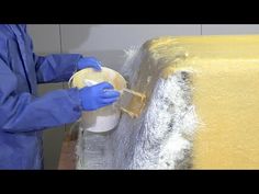 a person in blue gloves and protective clothing painting a piece of yellow material on a table