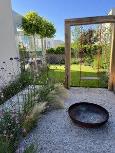 an outdoor area with gravel, plants and a swing