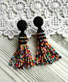 two pairs of colorful beaded earrings sitting on top of a white lace covered table