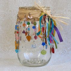 a mason jar filled with lots of different colored beads and charms hanging from it's lid