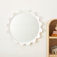 an elephant figurine stands next to a shelf with a round mirror on it