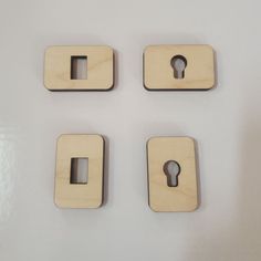 four wooden magnets with keys attached to them on a white surface and one has a keyhole in the middle