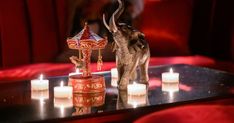 an elephant figurine sitting on top of a table next to some lit candles