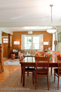 a dining room table and chairs in front of a fireplace with an area rug on the floor