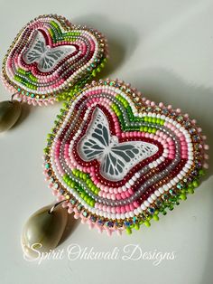 pair of earrings with beads and butterflies on them sitting on top of a white surface