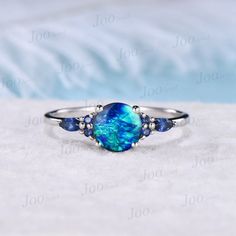 7mm Round Galaxy Blue Opal Engagement Ring Sterling Silver Cluster Blue Sapphire Ring Unique Anniversary Gift Blue Fire Opal Promise Rings 30 days non-hassle return policy. For returned items, there may be handcrafting and shipping fee deducted. DETAILS: - Material : 925 Sterling Silver (Hypoallergenic, Nickel Free, Tarnish Resistant)Solid 14k/18k gold,platinum PLEASE choose silver or platinum if you are allergic to nickel. - Main stone : 7mm Round cut blue opal - Accent Stone : blue sapphire - Blue Opal Promise Ring, Blue Opal Round Ring, Blue Round Opal Ring, Blue Opal Rings For Anniversary, Blue Opal Jewelry For Anniversary, Blue Opal Ring With Accent Stones, Blue Opal Anniversary Rings, Blue Round Band Jewelry Gift, Blue Opal Ring Gift