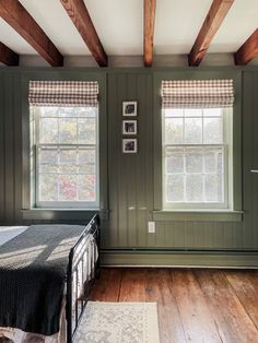 a bedroom with green walls and wooden beams on the ceiling, along with a bed