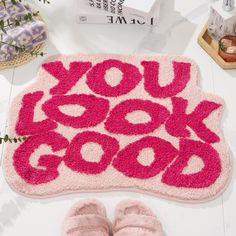 a pair of pink slippers sitting on top of a rug that says you look good