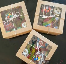 three boxes with pictures tied to them sitting on a black table next to each other