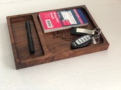 a wooden tray with two keys, a pen and some other items on top of it