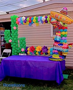 a purple table topped with balloons and an arch